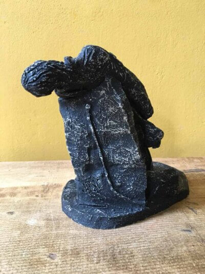 Ceramic sculpture of a rock guitarist painted black.