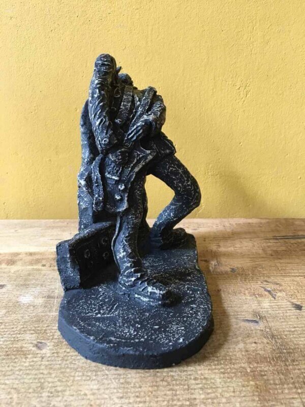 Ceramic sculpture of a rock guitarist painted black.