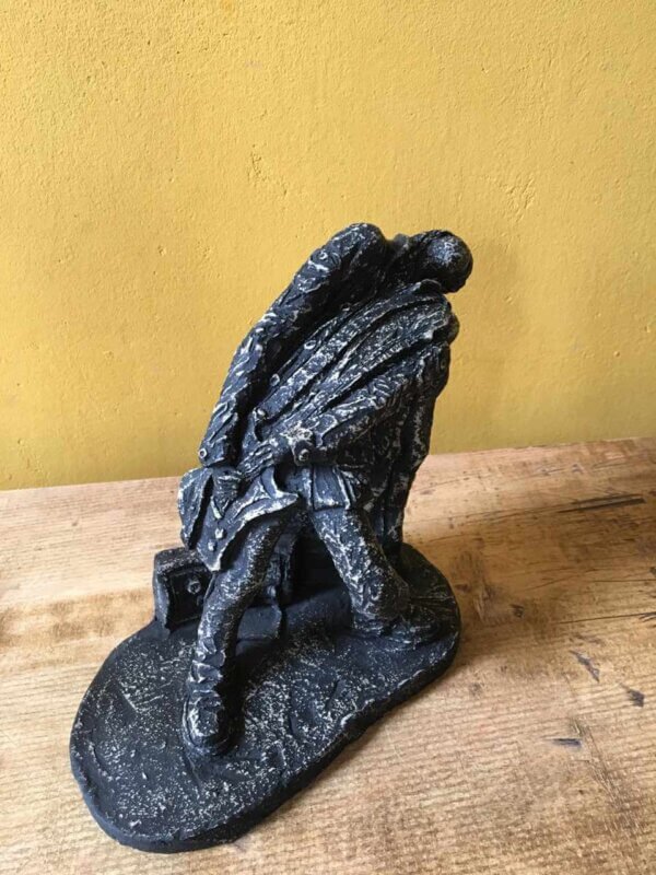 Ceramic sculpture of a rock guitarist painted black.