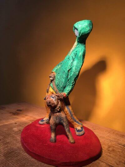 Ceramic sculpture of figure in green hoodie with a Staffordshire bull terrier on a lead.