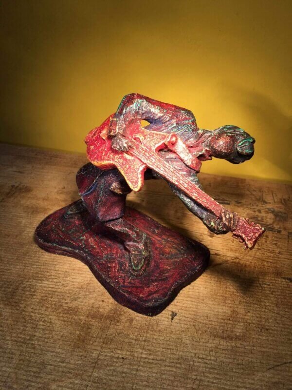 Ceramic sculpture of a rockabilly guitarist painted red.