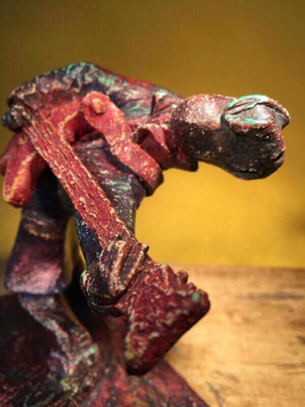 Ceramic sculpture of a rockabilly guitarist painted red.