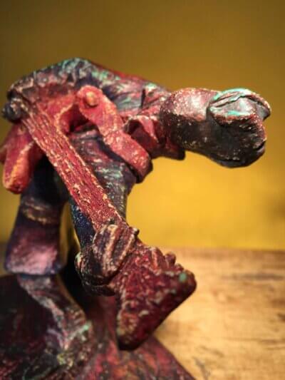 Ceramic sculpture of a rockabilly guitarist painted red.