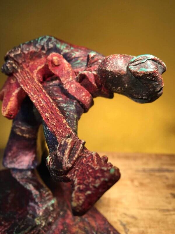 Ceramic sculpture of a rockabilly guitarist painted red.