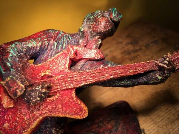 Ceramic sculpture of a rockabilly guitarist painted red.