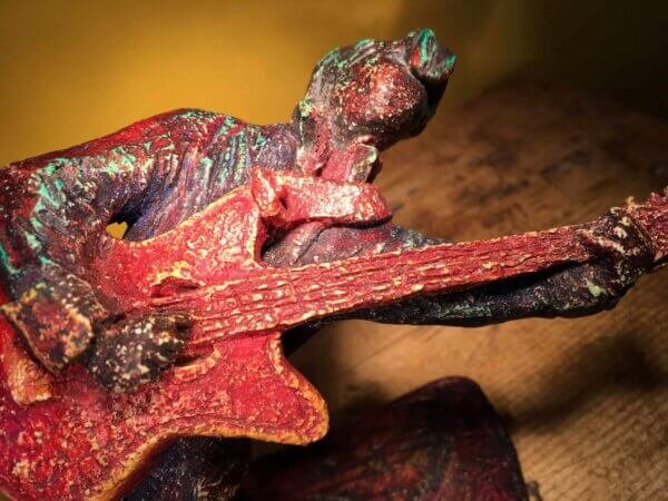 Ceramic sculpture of a rockabilly guitarist painted red.