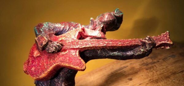 Ceramic sculpture of a rockabilly guitarist painted red.