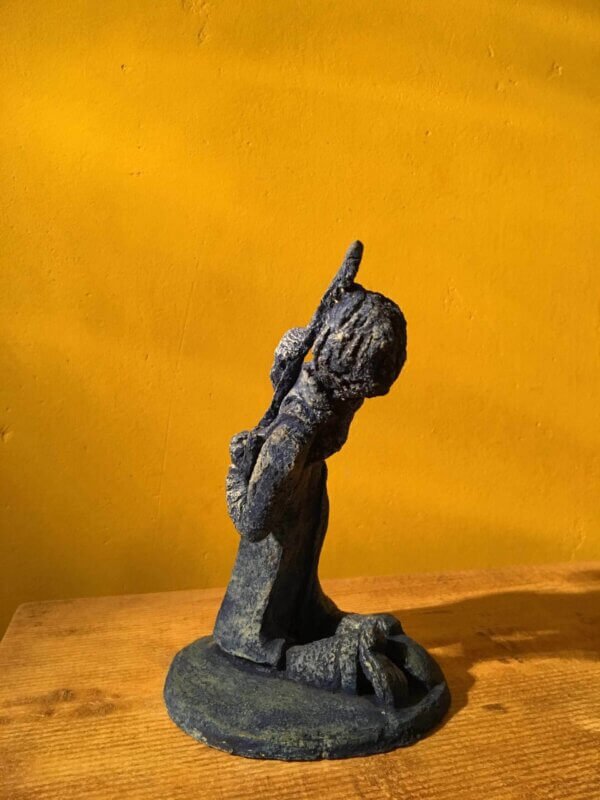 Ceramic sculpture of a kneeling guitarist painted blue.