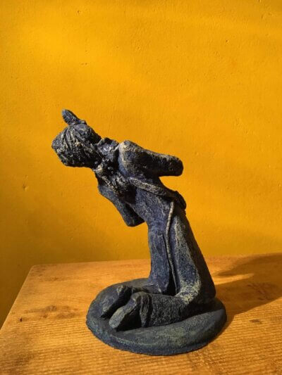 Ceramic sculpture of a kneeling guitarist painted blue.