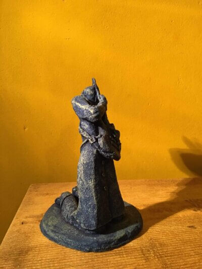 Ceramic sculpture of a kneeling guitarist painted blue.
