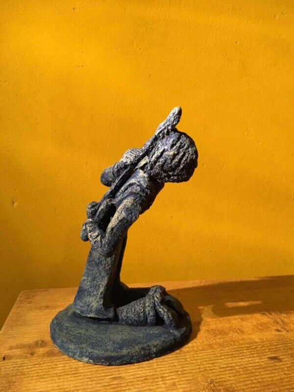 Ceramic sculpture of a kneeling guitarist painted blue.