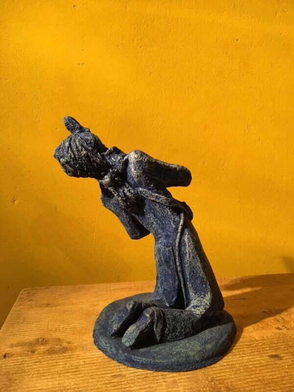 Ceramic sculpture of a kneeling guitarist painted blue.