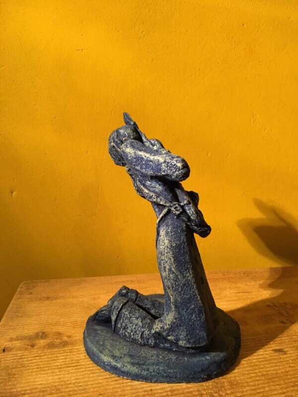 Ceramic sculpture of a kneeling guitarist painted blue.