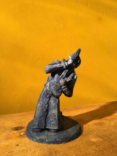 Ceramic sculpture of a kneeling guitarist painted blue.