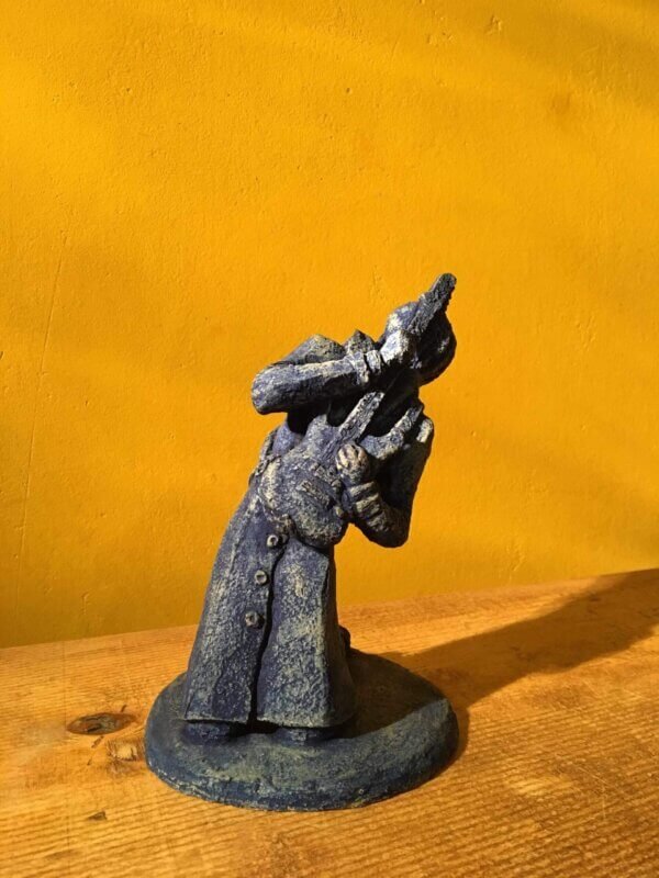 Ceramic sculpture of a kneeling guitarist painted blue.