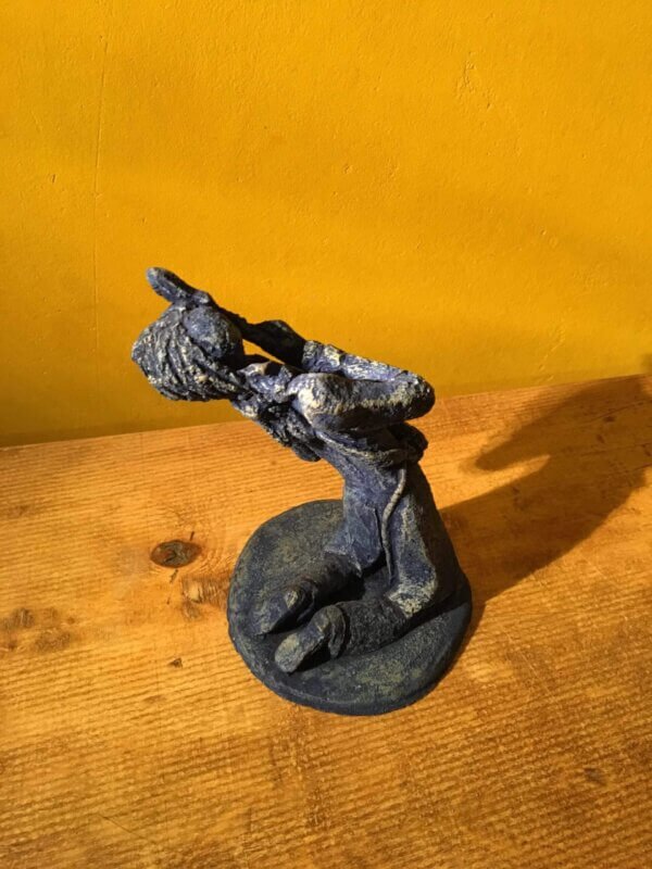 Ceramic sculpture of a kneeling guitarist painted blue.