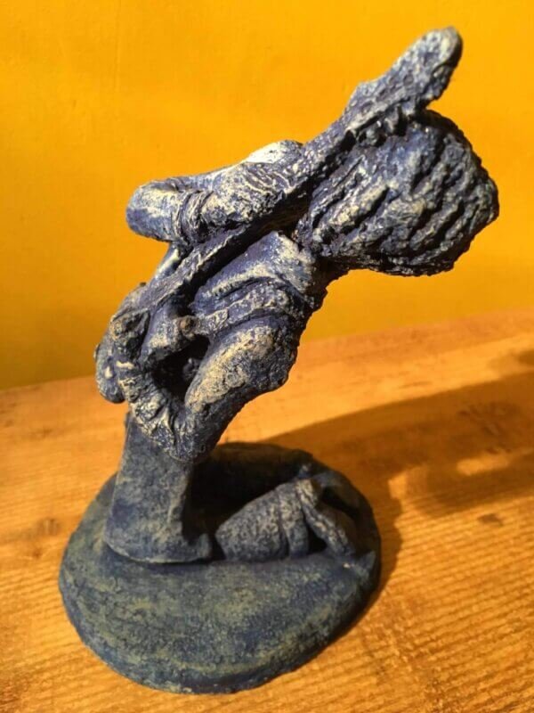 Ceramic sculpture of a kneeling guitarist painted blue.