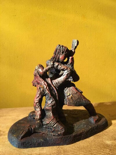 Ceramic sculpture of a singer and guitarist painted red.
