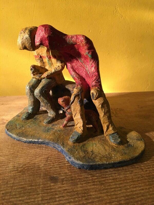 Ceramic sculpture of two figures sitting in hoodies looking at mobile phones with a dog at their feet.