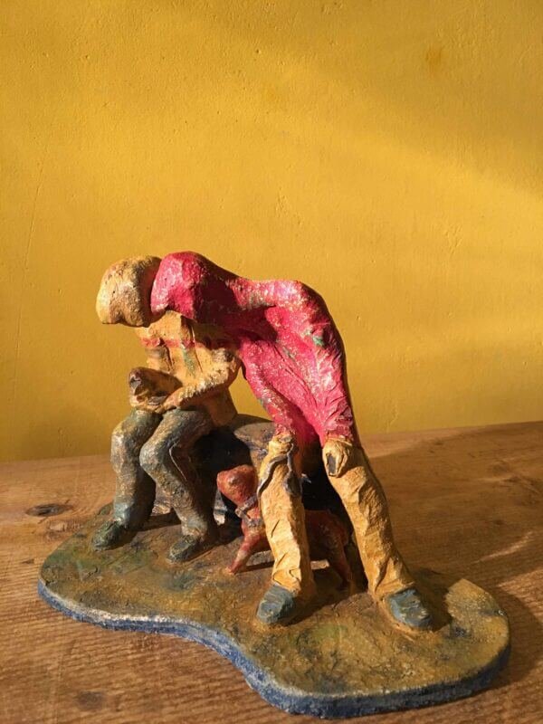 Ceramic sculpture of two figures sitting in hoodies looking at mobile phones with a dog at their feet.