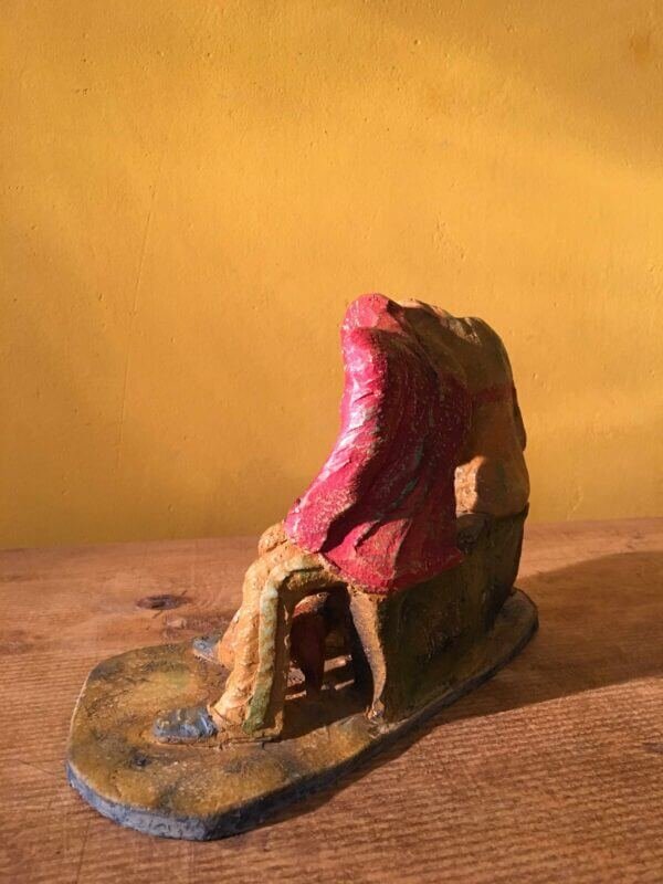 Ceramic sculpture of two figures sitting in hoodies looking at mobile phones with a dog at their feet.