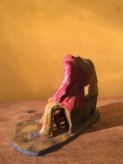 Ceramic sculpture of two figures sitting in hoodies looking at mobile phones with a dog at their feet.