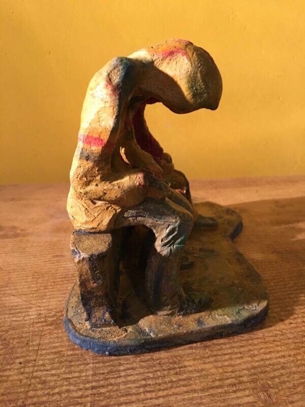 Ceramic sculpture of two figures sitting in hoodies looking at mobile phones with a dog at their feet.