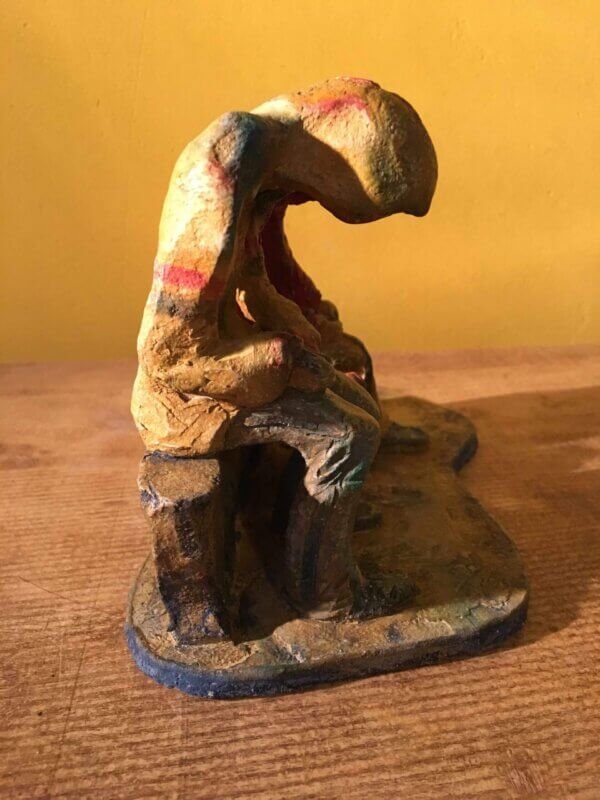Ceramic sculpture of two figures sitting in hoodies looking at mobile phones with a dog at their feet.