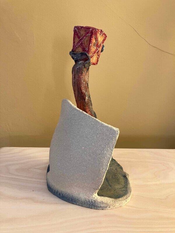 ceramic sculpture of a figure with a box and goggles on its head