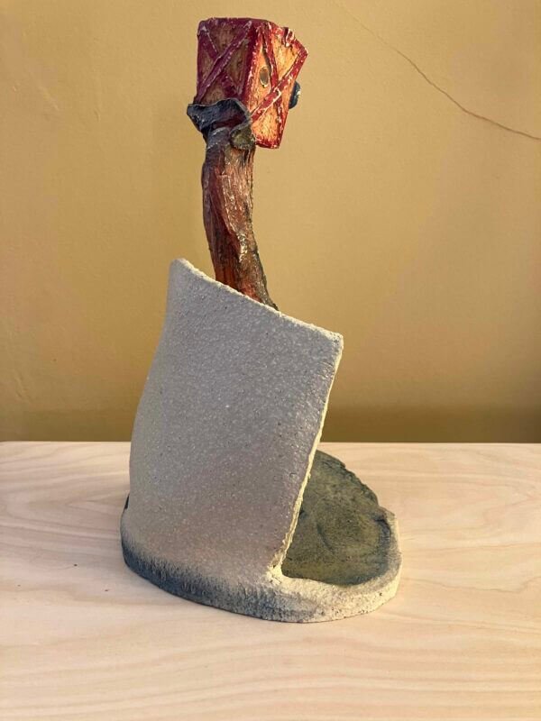 ceramic sculpture of a figure with a box and goggles on its head