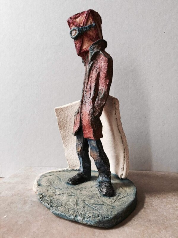 ceramic sculpture of a figure with a box and goggles on its head