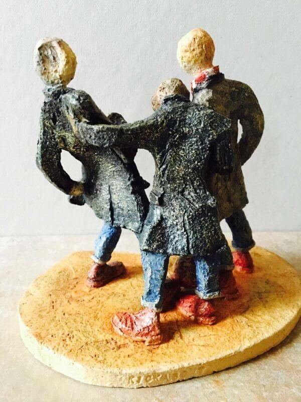 ceramic sculpture of figures in coats kicking a football around